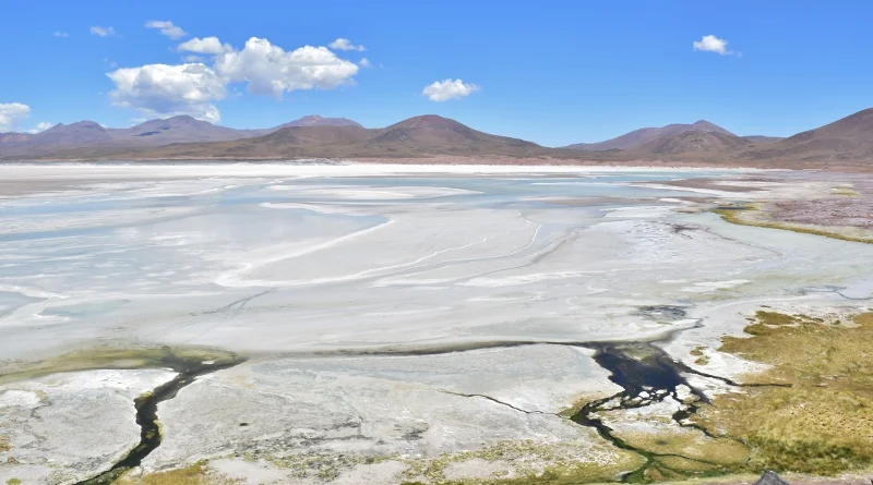 Contraste de roca roja, salar blanco y agua azul en Piedras Rojas